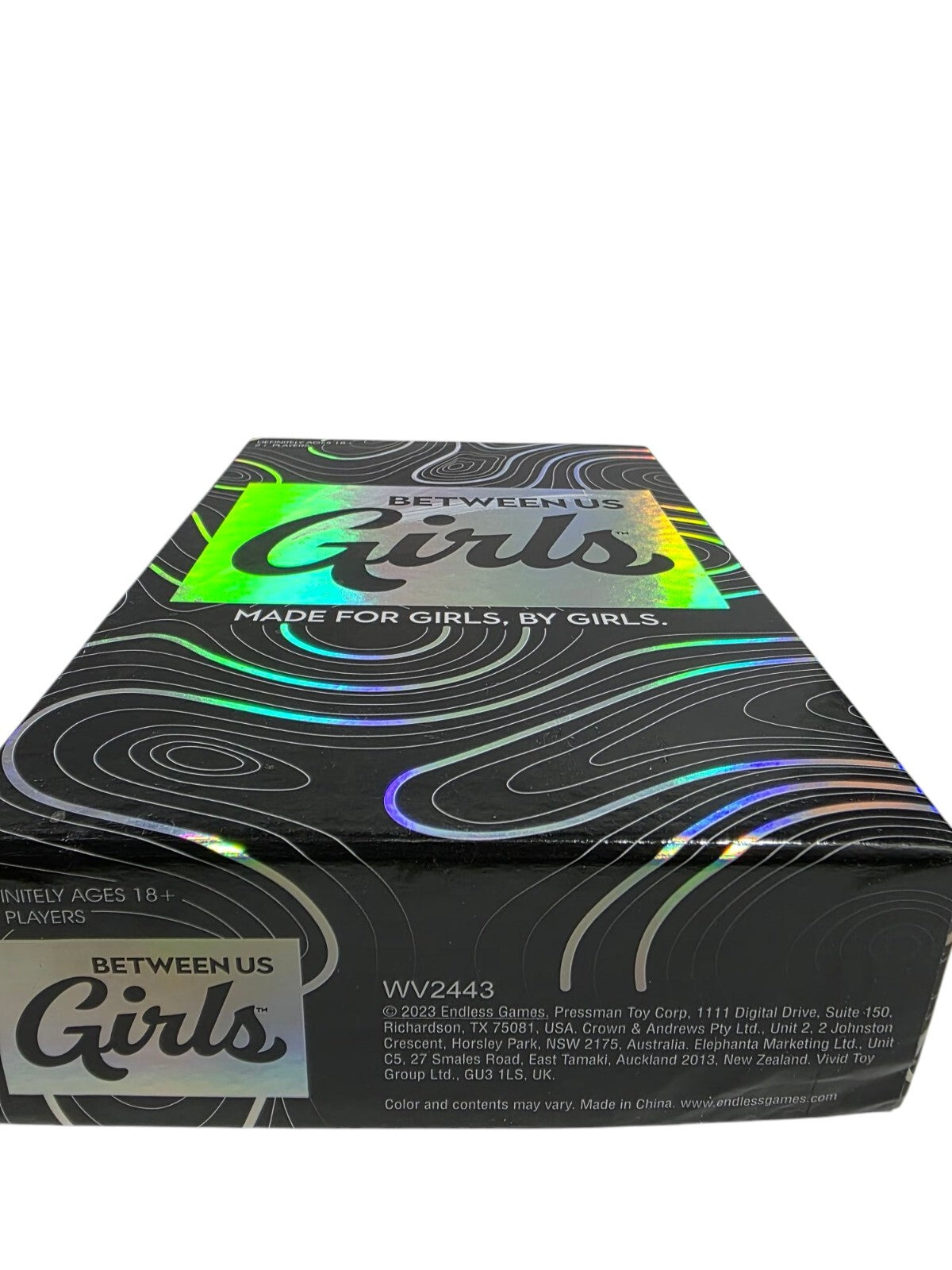 Between Us Girls game box designed for 2+ players, featuring a colorful, holographic design and fun themes.