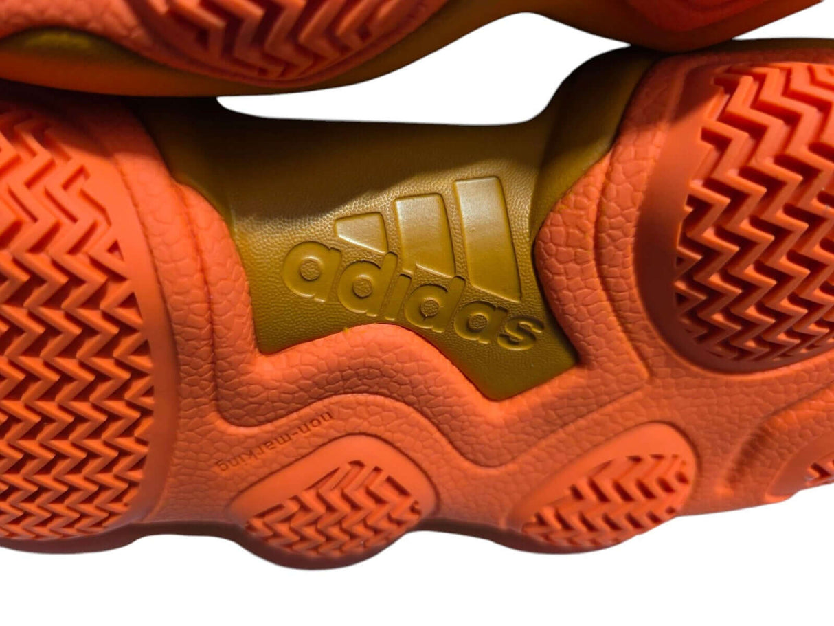Close-up of orange Adidas basketball shoe outsole with logo and textured pattern.